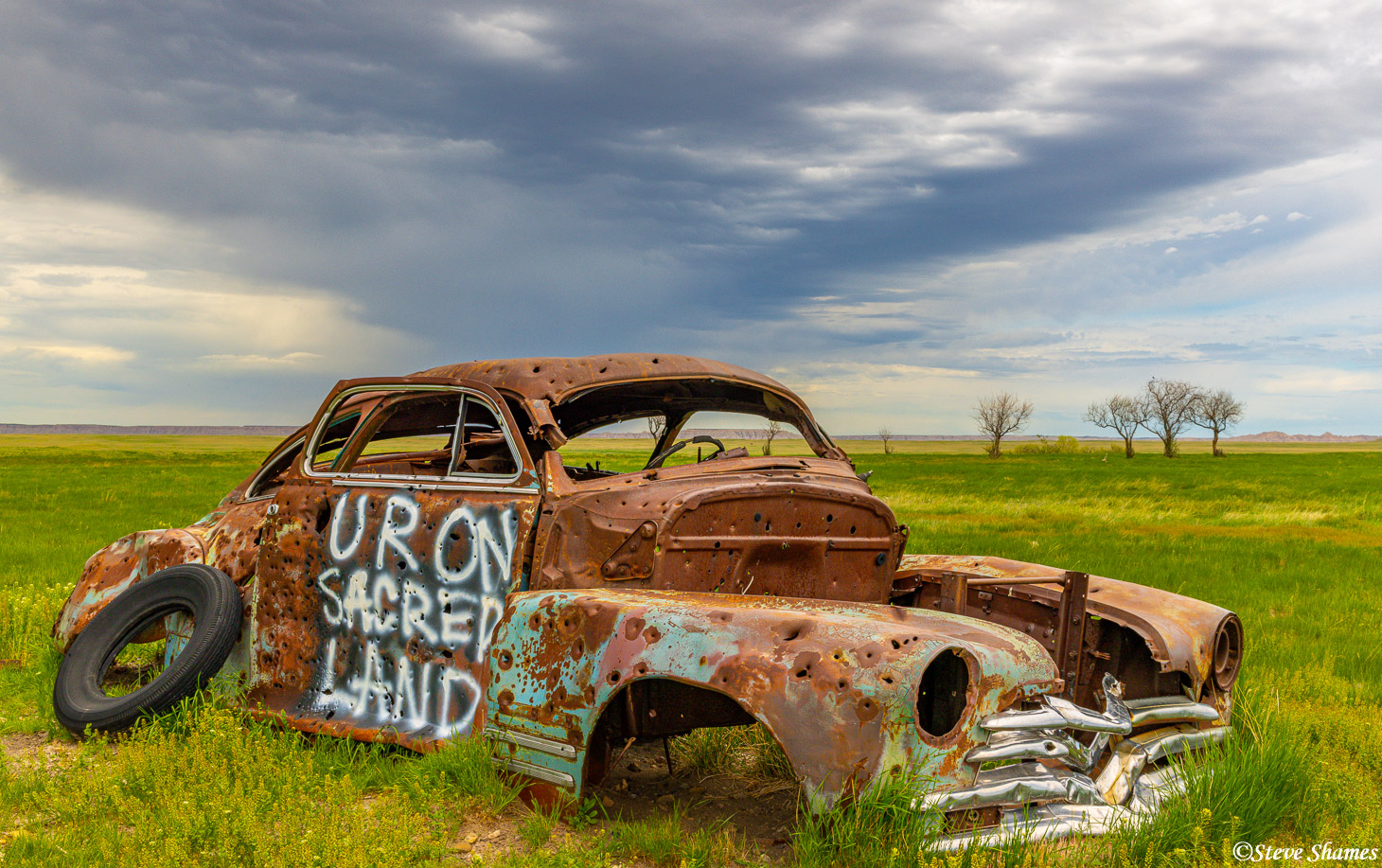 This bullet riddled junked car says "Ur on sacred land". I am assuming somebody wrote that so this car might be removed. This...
