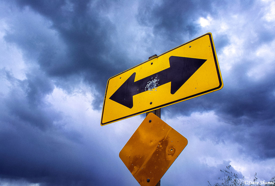 With a threatening looking sky behind it, this&nbsp;arrow sign shows it has survived a close encounter with a shotgun blast.