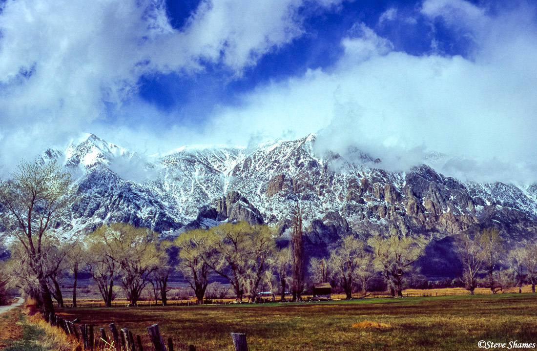 View from the Owens Valley of snow covered mountains shrouded with clouds.