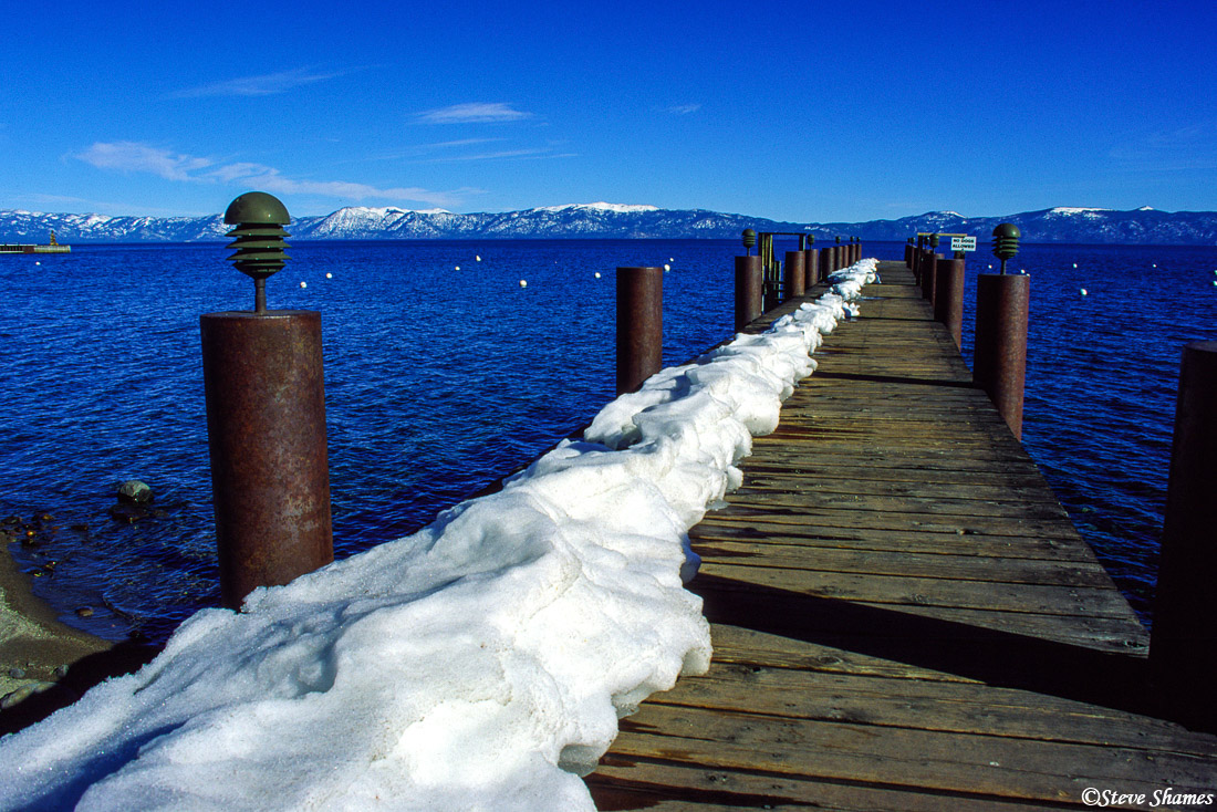 A snowy pier juts into the lake.