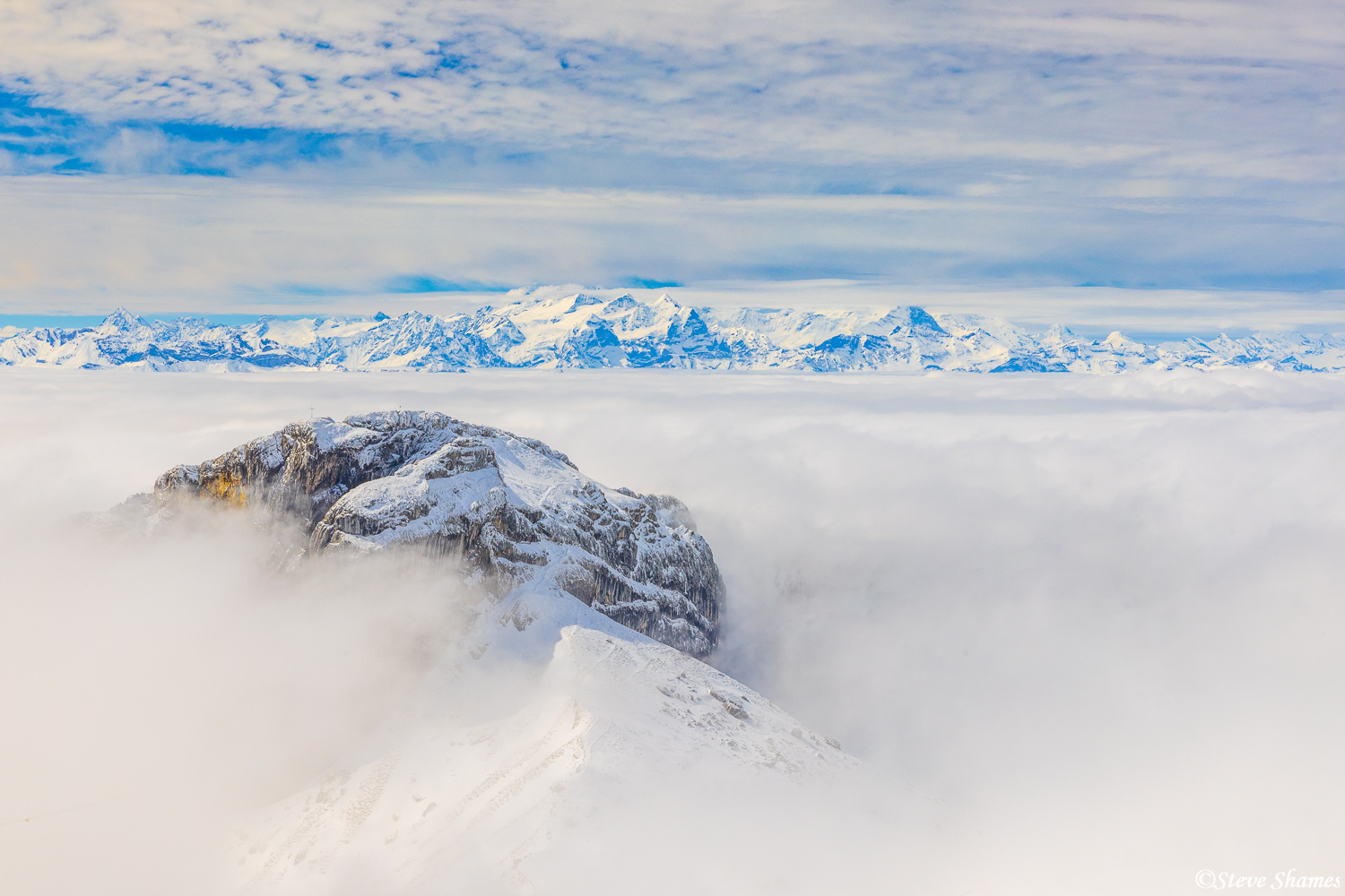 The view from Mount Pilatus, with a closer mountain in front and the Swiss Alps in the distance.